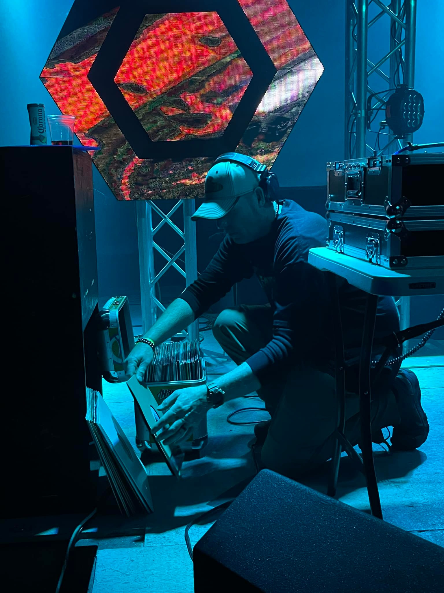 DJ Natural Nate® pulling vinyl from crates on stage with red hexagon LED screen behind
